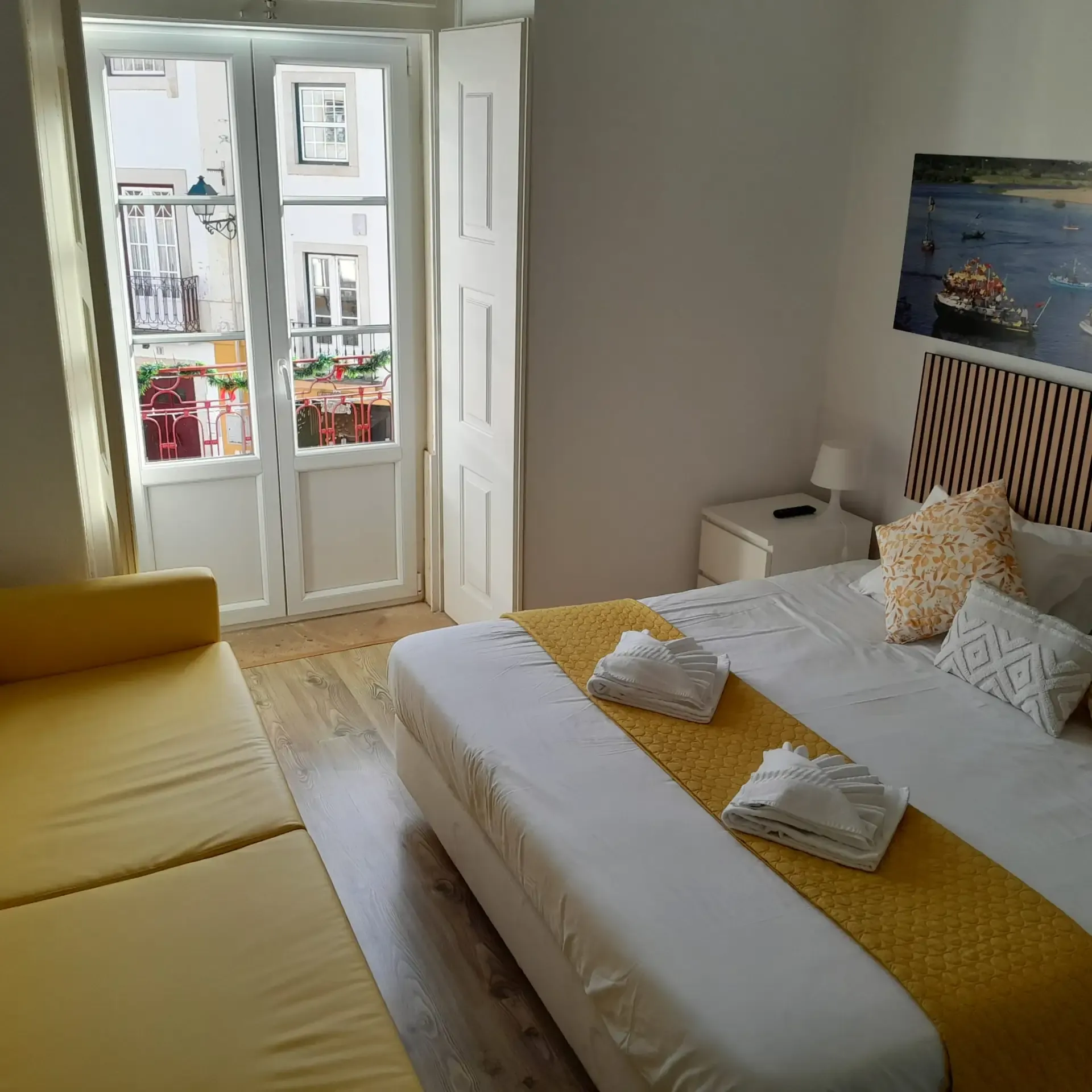 Deluxe room — king-size bed with a river panel, yellow sofa bed and door to the street