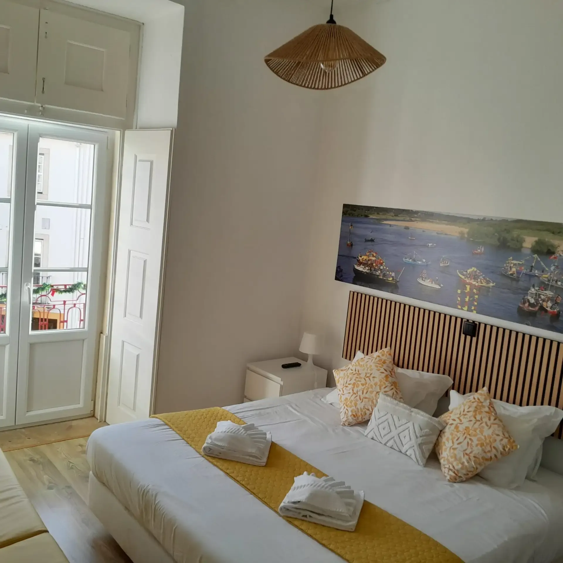 Deluxe room — bed with a panel of boats on the river and the balcony door