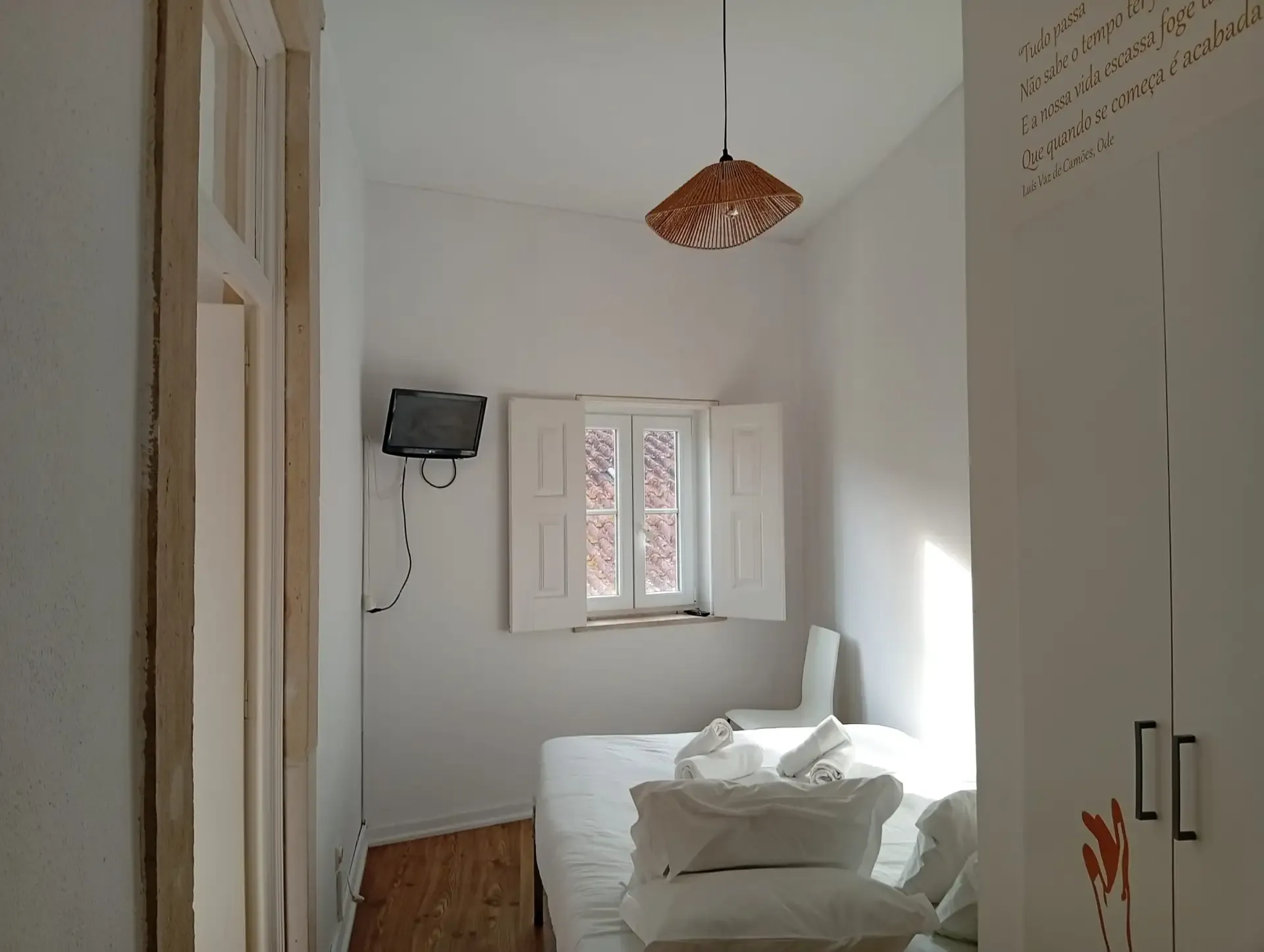 Family room — bed by the window, TV and a Camões ode written on the wardrobe